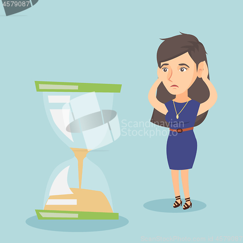 Image of Desperate business woman looking at hourglass.