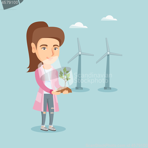 Image of Caucasian worker of wind farm holding small plant.