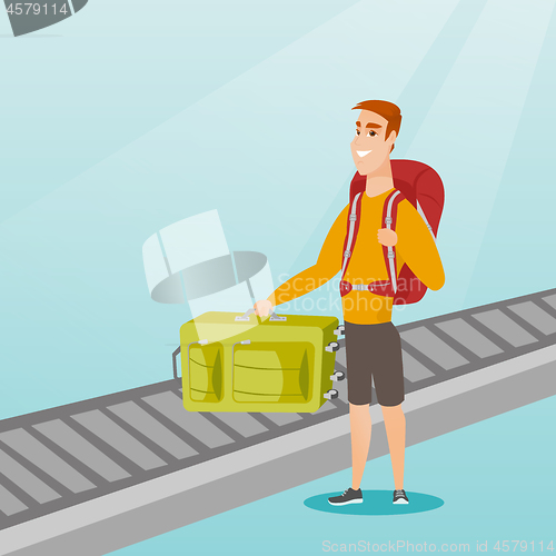 Image of Man picking up suitcase from conveyor belt.