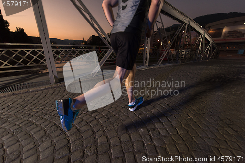 Image of man jogging across the bridge in the city