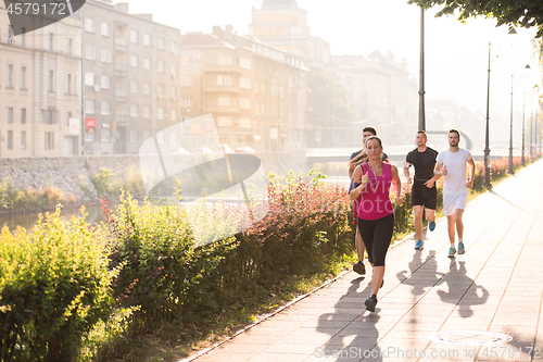 Image of group of young people jogging in the city