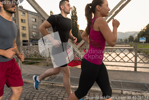 Image of group of young people jogging across the bridge