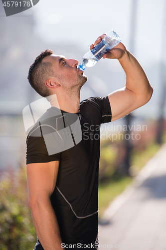 Image of man drinking water from a bottle after jogging