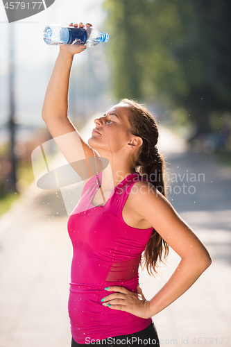 Image of woman pouring water from bottle on her head