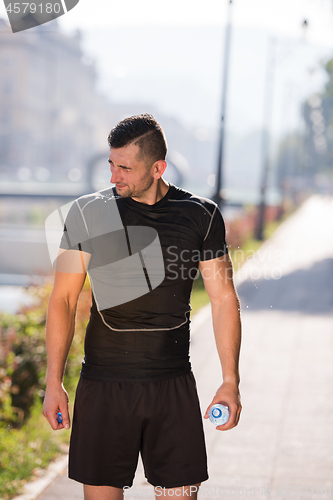 Image of man pouring water from bottle on his head