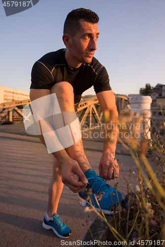 Image of man tying running shoes laces