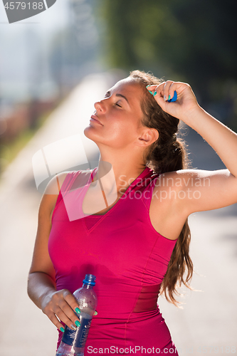 Image of woman drinking water from a bottle after jogging