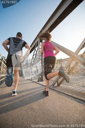 Image of young couple jogging across the bridge in the city