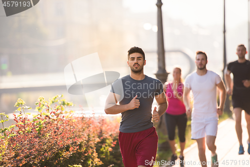 Image of group of young people jogging in the city