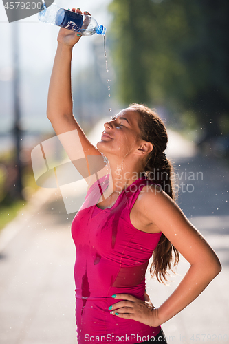 Image of woman pouring water from bottle on her head