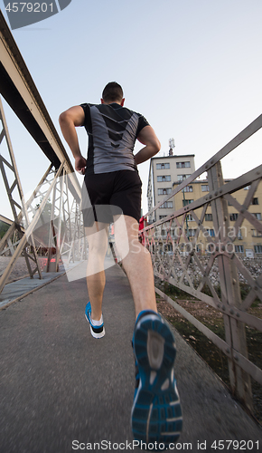 Image of man jogging across the bridge at sunny morning