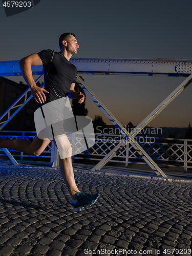 Image of man jogging across the bridge in the city