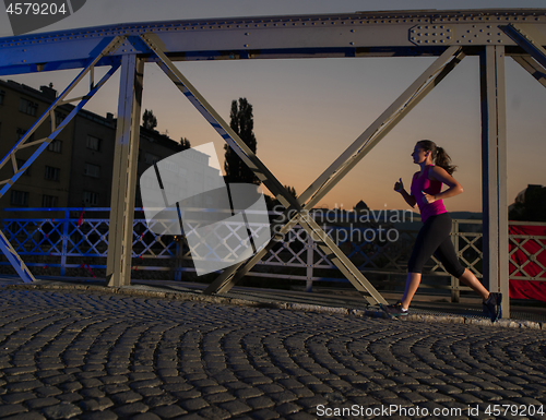 Image of woman jogging across the bridge in the city