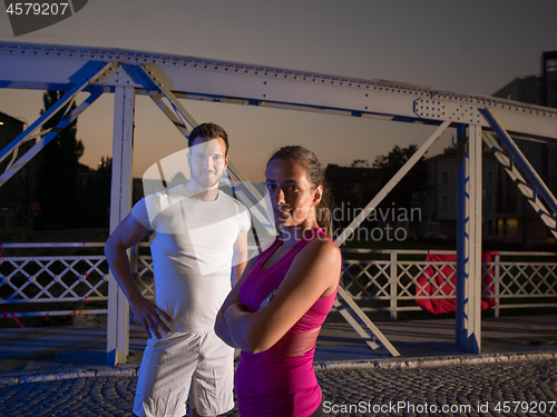 Image of portrait of couple jogging across the bridge in the city