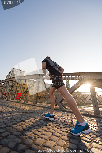 Image of man jogging across the bridge at sunny morning