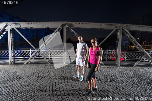 Image of couple jogging across the bridge in the city