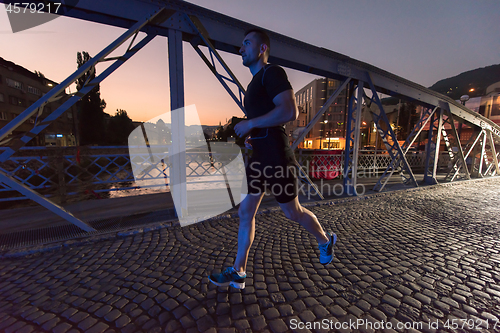 Image of man jogging across the bridge in the city