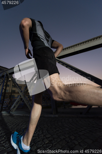 Image of man jogging across the bridge in the city