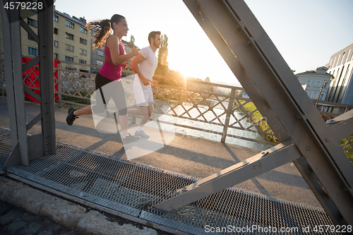 Image of young couple jogging across the bridge in the city