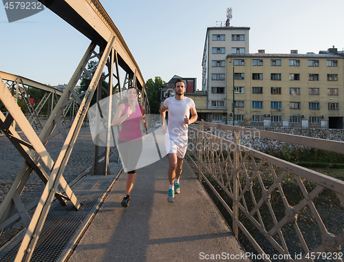 Image of young couple jogging across the bridge in the city