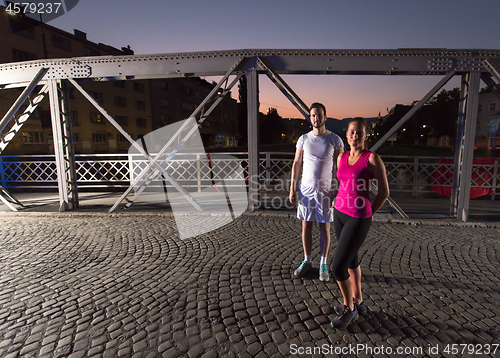 Image of couple jogging across the bridge in the city