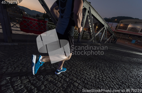 Image of man jogging across the bridge in the city