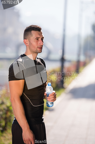 Image of man drinking water from a bottle after jogging
