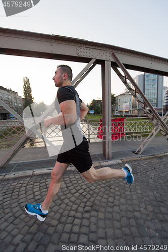 Image of man jogging across the bridge at sunny morning