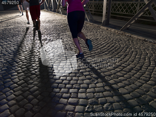 Image of young people jogging across the bridge