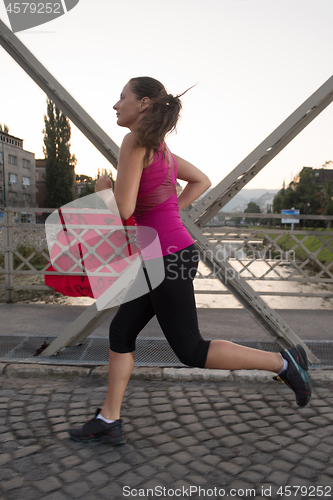 Image of woman jogging across the bridge at sunny morning