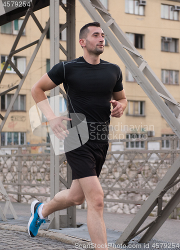 Image of man jogging across the bridge at sunny morning