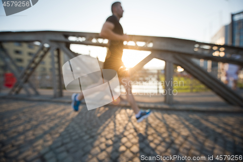 Image of man jogging across the bridge at sunny morning