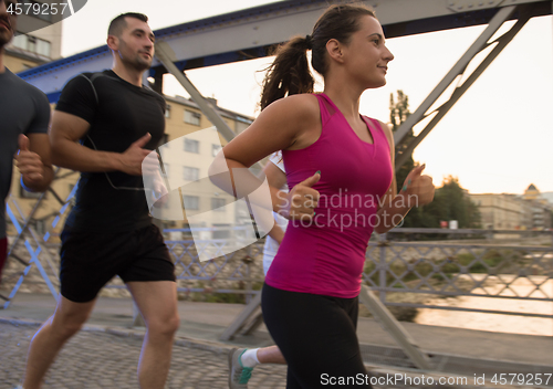 Image of group of young people jogging across the bridge