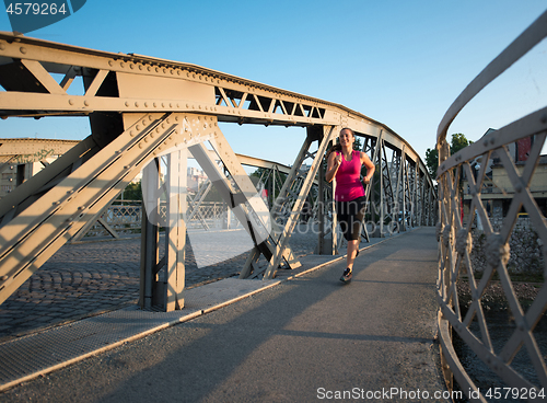 Image of woman jogging across the bridge at sunny morning