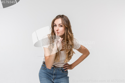 Image of The young woman whispering a secret behind her hand