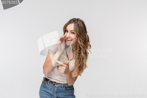 Image of The young woman whispering a secret behind her hand