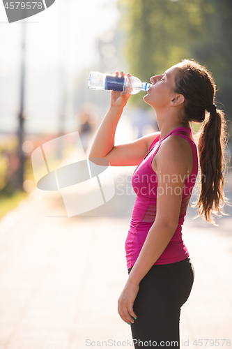 Image of woman drinking water from a bottle after jogging