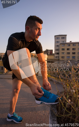 Image of man tying running shoes laces