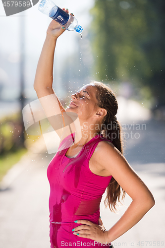 Image of woman pouring water from bottle on her head