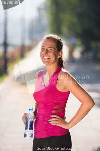 Image of woman drinking water from a bottle after jogging