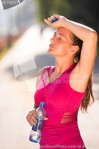 Image of woman drinking water from a bottle after jogging