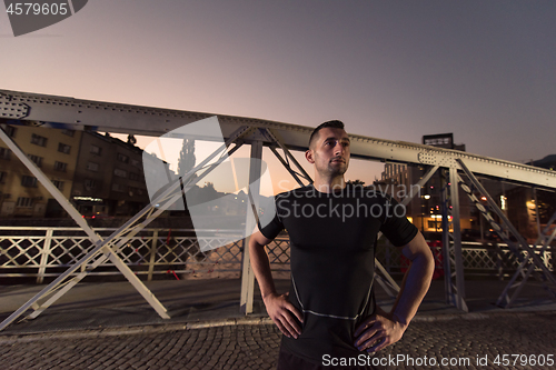 Image of man jogging across the bridge in the city