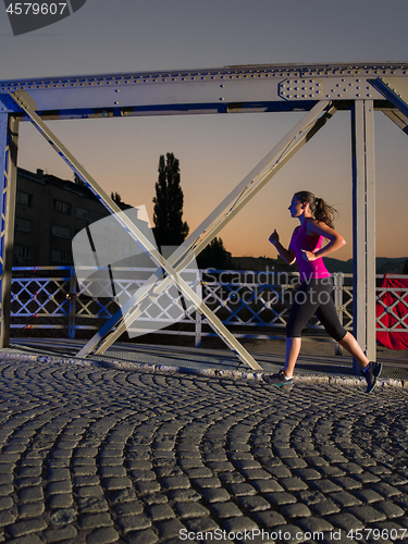 Image of woman jogging across the bridge in the city