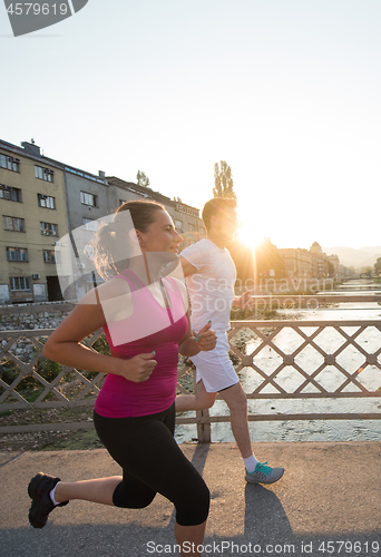 Image of young couple jogging across the bridge in the city