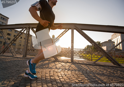 Image of man jogging across the bridge at sunny morning