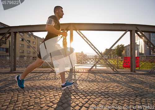 Image of man jogging across the bridge at sunny morning