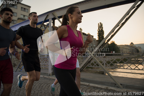 Image of group of young people jogging across the bridge