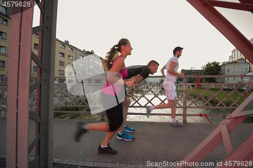 Image of group of young people jogging across the bridge