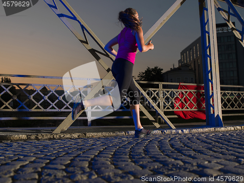 Image of woman jogging across the bridge in the city