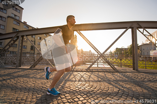 Image of man jogging across the bridge at sunny morning